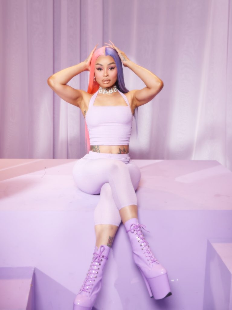 Blac Chyna wearing a pastel purple outfit with split pink and blue hair, ranked among leading Lightskin OnlyFans creators.