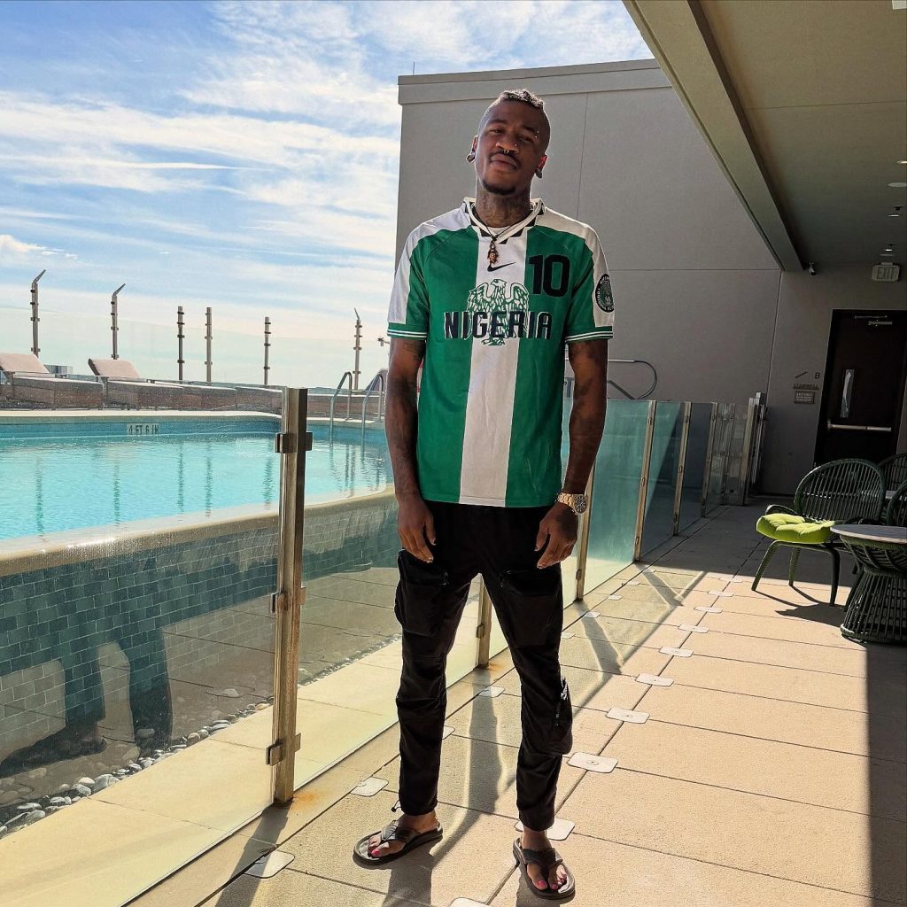 Nigerian OnlyFans creator Chimereuche-Jackson Nwokeoma wearing a green and white Nigeria football jersey while posing outdoors by a swimming pool.