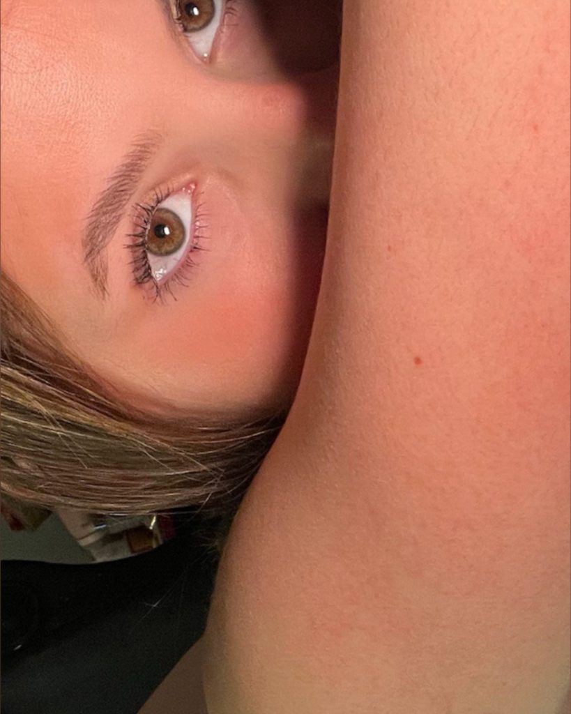Close-up, angled shot focusing on the brown eyes and eyelashes of a woman named Haley, with her arm partially raised in front of the camera.