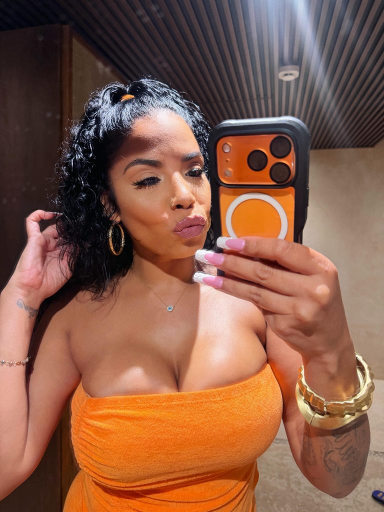 Havana Ginger, a popular Cuban OnlyFans creator, taking a close-up mirror selfie in an orange tube dress.