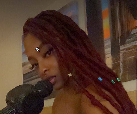 Nigerian OnlyFans creator Nigerian Gypsy posing with long reddish-brown locs holding a bedazzled microphone.