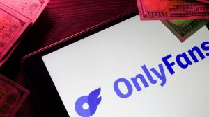 Tablet displaying the OnlyFans logo surrounded by US hundred-dollar bills, illustrating OnlyFans creator earnings AI concepts.