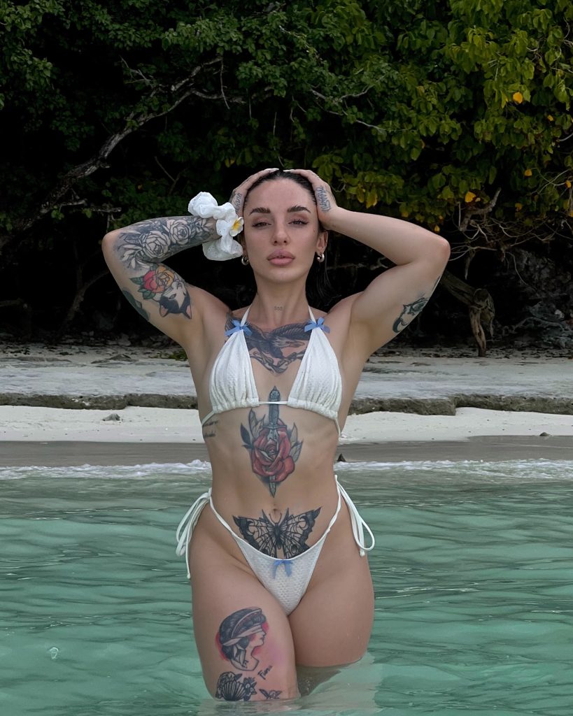 Vega Perez in a white bikini standing in tropical shallow water, highlighted as a Big Ass OnlyFans creator.