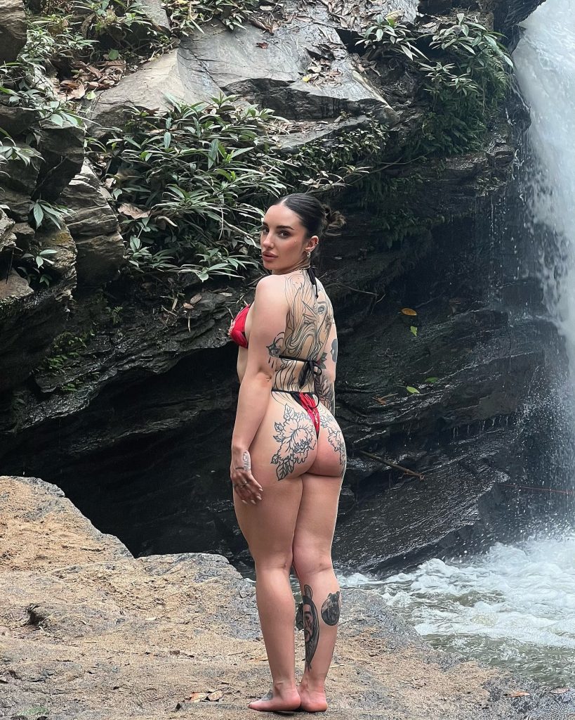 Vega Perez posing in a red bikini near a waterfall, featured as a top Big Ass OnlyFans creator.