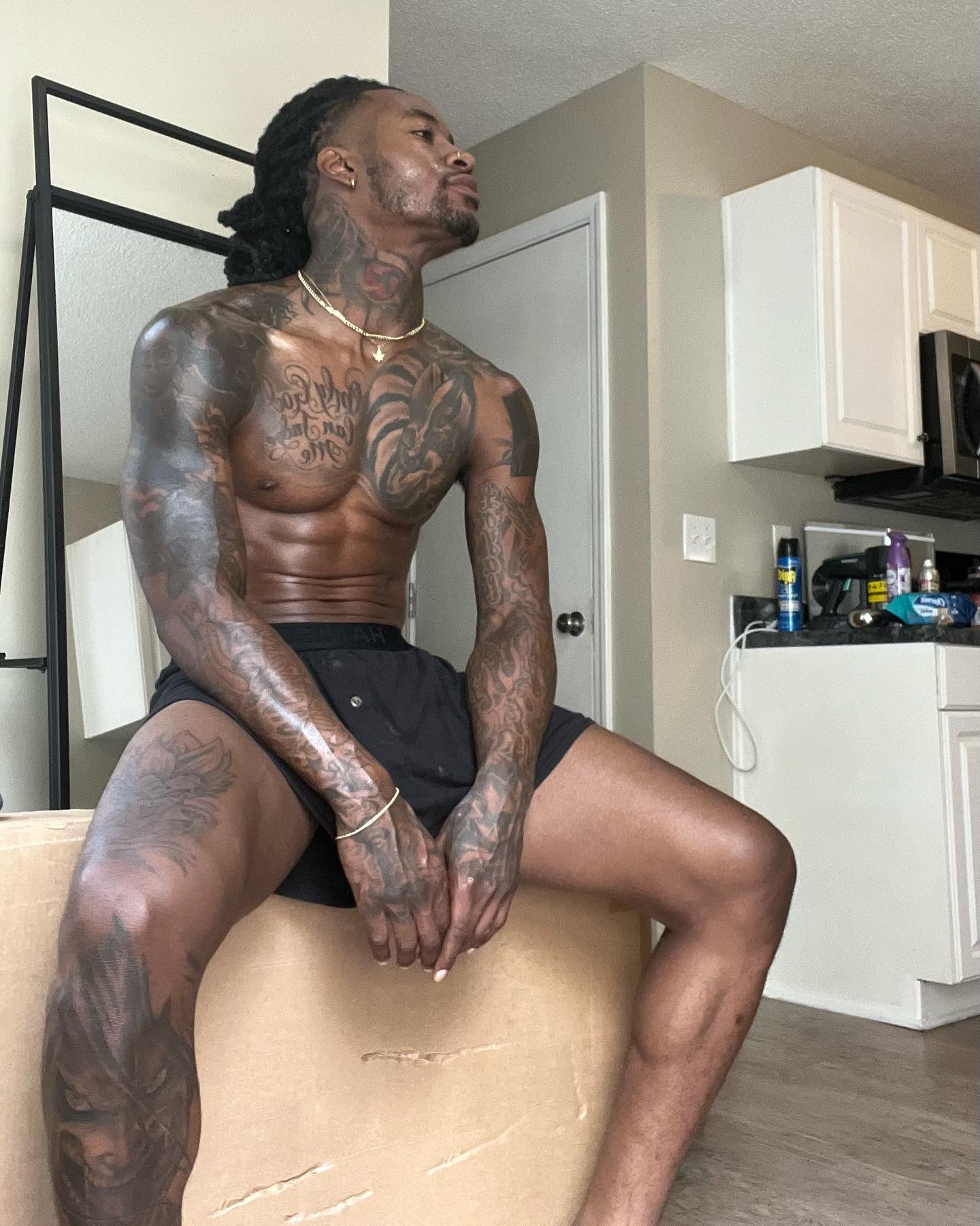 Heavily tattooed fitness model sitting indoors, showcasing top content creators for best black onlyfans.