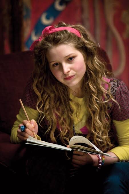 Jessie Cave Harry Potter character Lavender Brown holding a pencil and notepad in the Gryffindor common room.