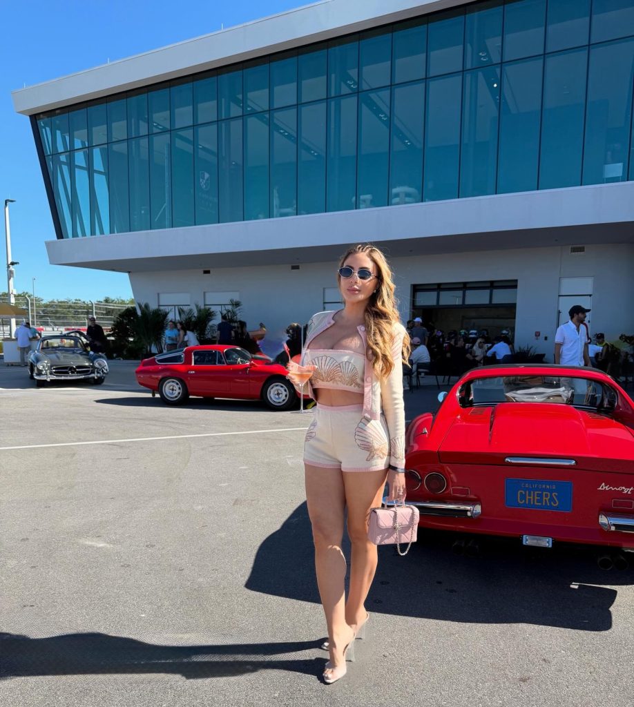 Full-body photo of Larsa Pippen in a matching seashell print knit set at an outdoor classic car show