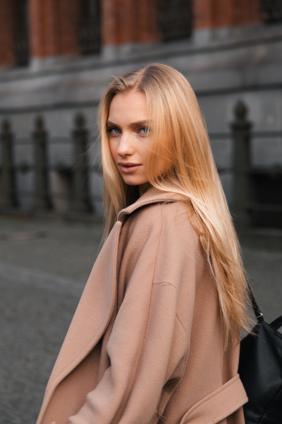 Elegant blonde woman in urban fashion setting with city backdrop