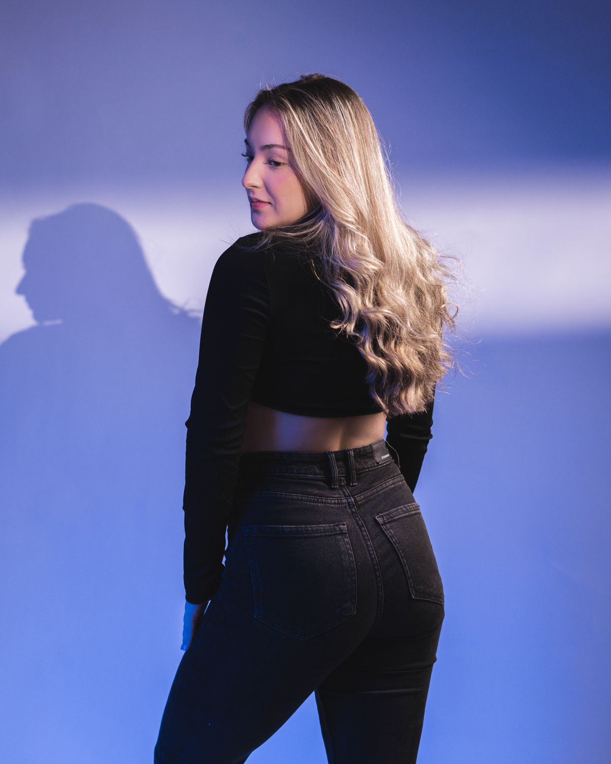 Stylish blonde woman posing in bold fashion against blue background