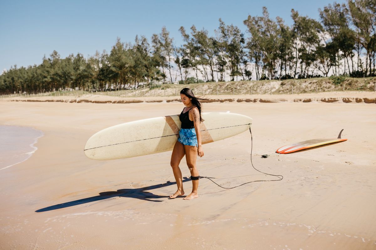 Woman carrying surfboard on sunny beach lifestyle content