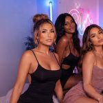 A group of five diverse women posing together in a studio setting, illustrating an article discussing amateur vs professional OnlyFans content creators.