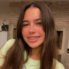 A headshot portrait of a smiling young woman with long brown hair, illustrating a list of the best petite OnlyFans creators.