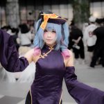 Cosplayer in colorful anime-inspired costume performing at an outdoor convention gathering