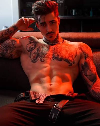 Jake Andrich displaying his tattooed physique indoors, a well-known personality on Canadian OnlyFans
