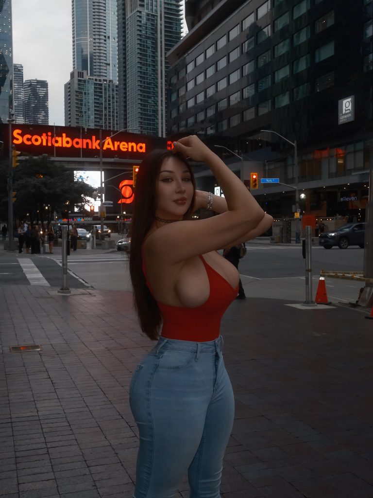 Louisa Khovanski in a tight red top and blue jeans posing on a city street near Scotiabank Arena – twitch streamers with onlyfans